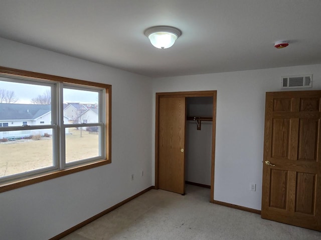 unfurnished bedroom featuring baseboards, visible vents, a closet, and light colored carpet