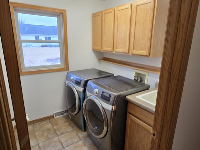 clothes washing area featuring visible vents, baseboards, cabinet space, stone finish flooring, and washing machine and clothes dryer