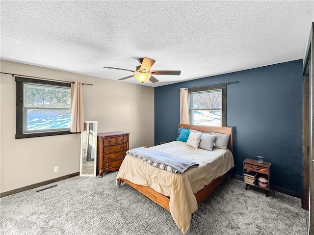 bedroom featuring ceiling fan, a textured ceiling, carpet floors, visible vents, and baseboards