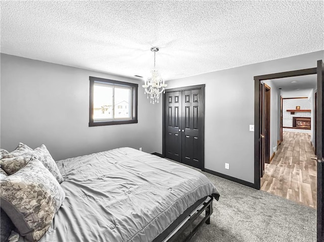 carpeted bedroom with a textured ceiling, a closet, an inviting chandelier, and baseboards