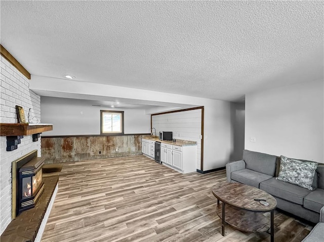 living area with wainscoting, wood walls, a textured ceiling, and light wood finished floors