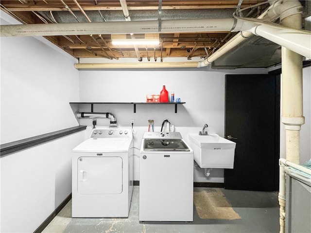 washroom with laundry area, baseboards, a sink, and independent washer and dryer