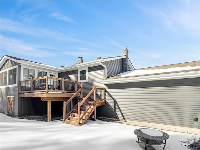 snow covered house featuring a patio area, stairs, a chimney, and a deck