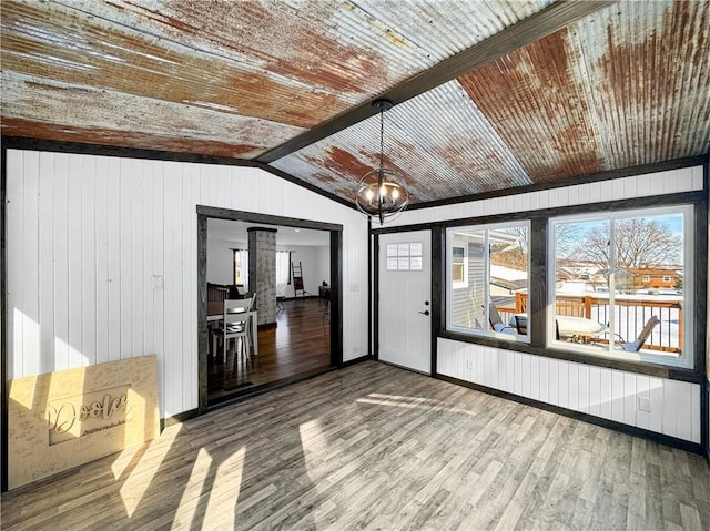 interior space featuring lofted ceiling with beams, an inviting chandelier, wood ceiling, wood walls, and wood finished floors