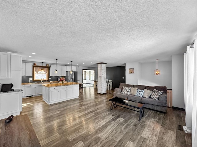 living area with a healthy amount of sunlight, ornate columns, visible vents, and wood finished floors