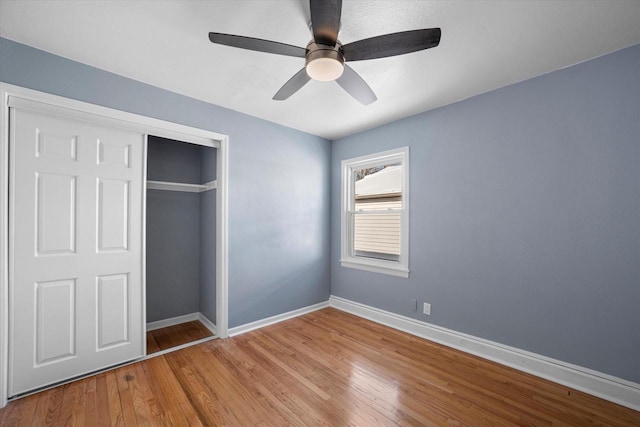 unfurnished bedroom featuring ceiling fan, a closet, light wood-style flooring, and baseboards