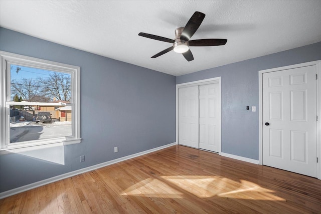 unfurnished bedroom with baseboards, ceiling fan, wood finished floors, a textured ceiling, and a closet