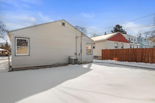 snow covered property with fence and central air condition unit