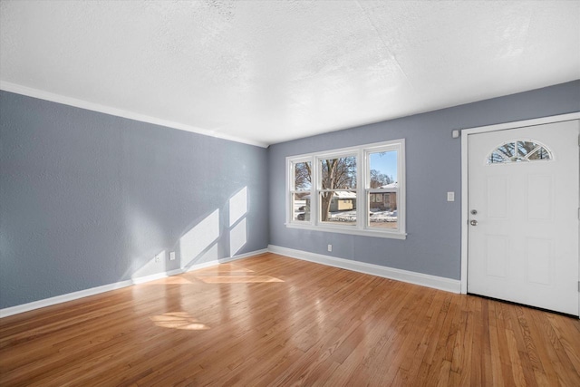 entrance foyer featuring a textured ceiling, a textured wall, wood finished floors, and baseboards