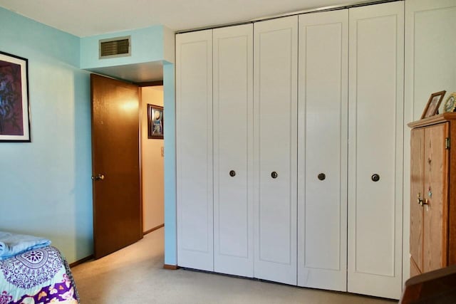 bedroom with light colored carpet, a closet, visible vents, and baseboards