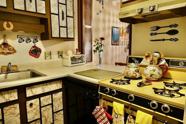 kitchen with a toaster, gas range, light countertops, under cabinet range hood, and a sink