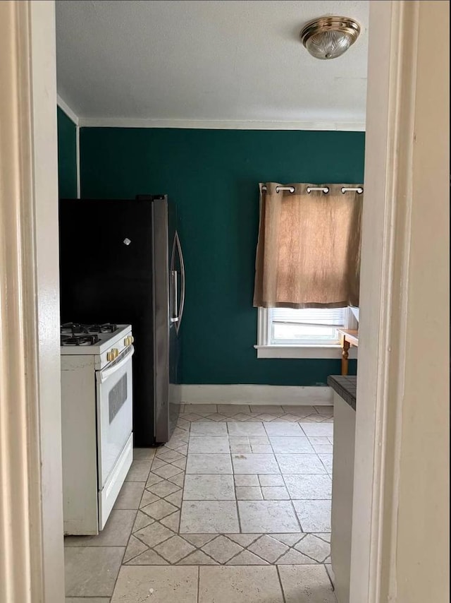 kitchen featuring crown molding, baseboards, and white gas range oven