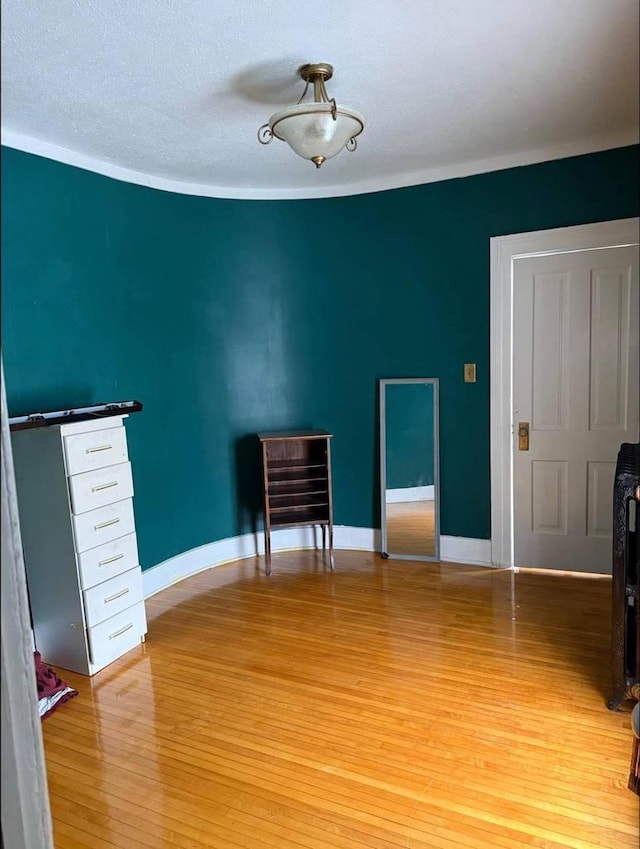 unfurnished room with light wood-style flooring, baseboards, and a textured ceiling