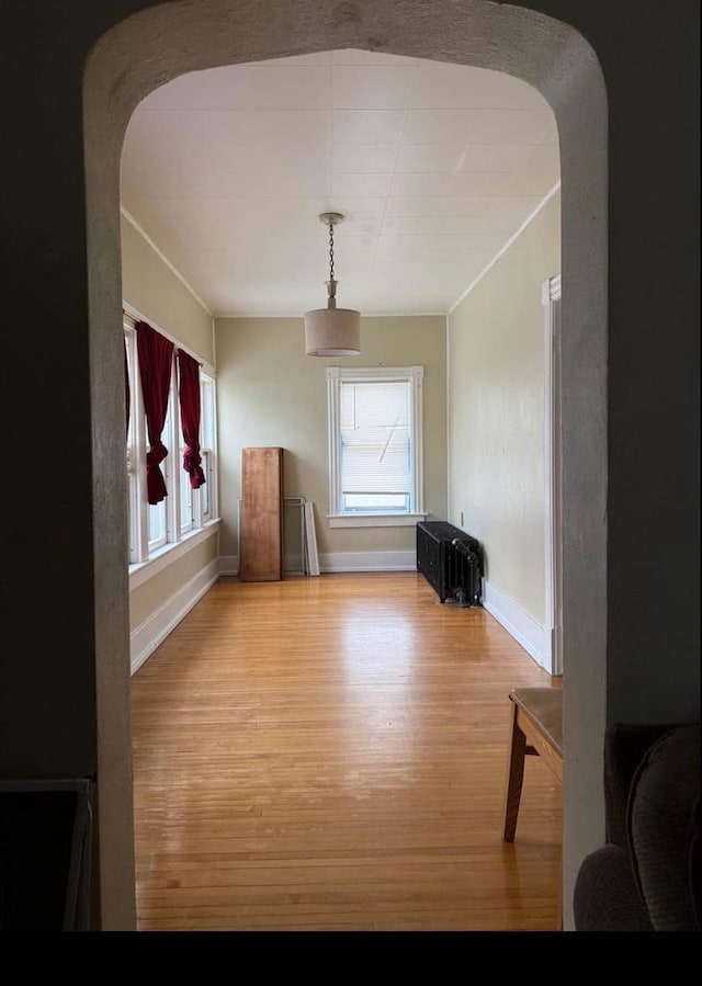 interior space with arched walkways, wood finished floors, and baseboards