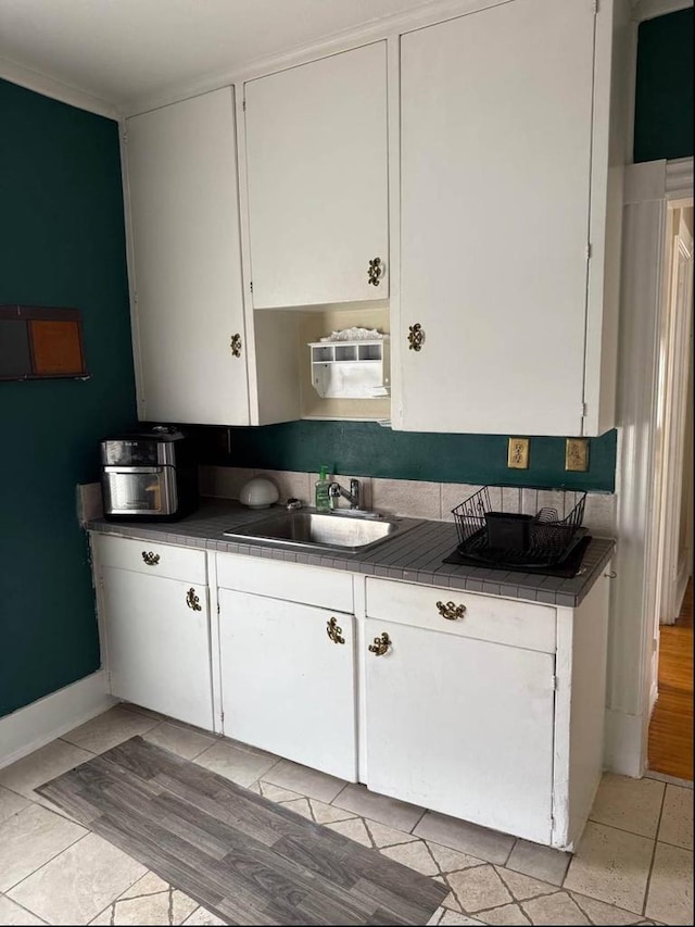 kitchen featuring a sink, tile counters, and white cabinetry