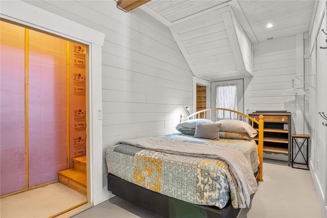 bedroom with vaulted ceiling and wooden walls