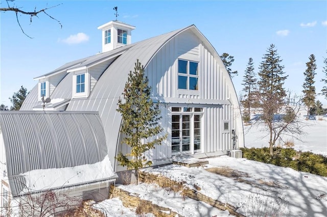 snow covered rear of property with metal roof and board and batten siding