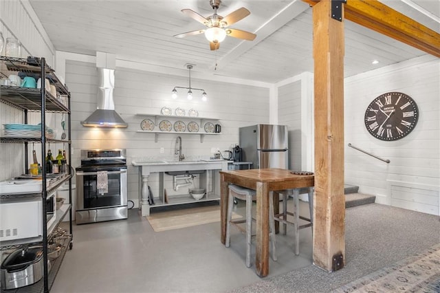 kitchen featuring stainless steel appliances, light countertops, wall chimney range hood, open shelves, and beam ceiling