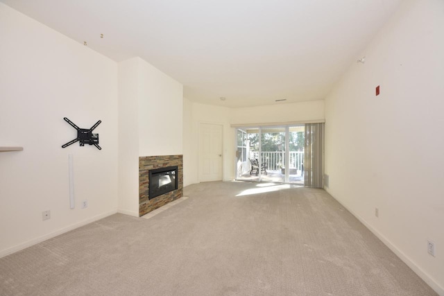 unfurnished living room with baseboards, a fireplace, and light colored carpet