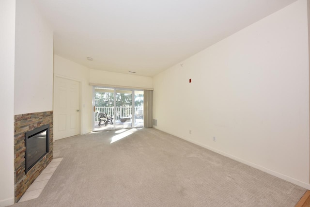 unfurnished living room featuring light carpet, a fireplace, and baseboards