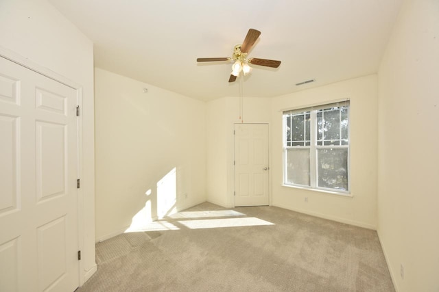 empty room with ceiling fan, visible vents, and light colored carpet