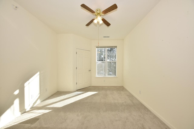 unfurnished room with light carpet, visible vents, baseboards, and ceiling fan