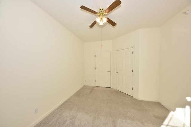 unfurnished room featuring a ceiling fan, light colored carpet, and baseboards