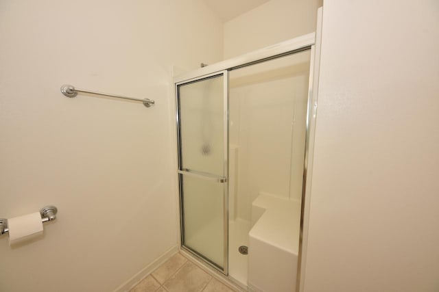 bathroom with a stall shower, baseboards, and tile patterned floors