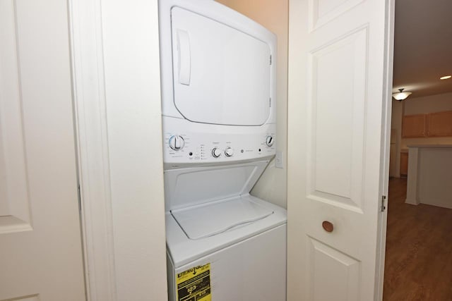 laundry area featuring laundry area, stacked washing maching and dryer, and wood finished floors