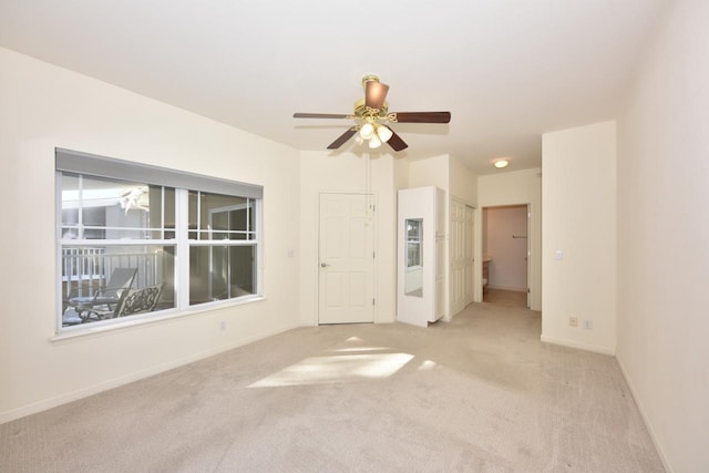 spare room with a ceiling fan, light colored carpet, and baseboards