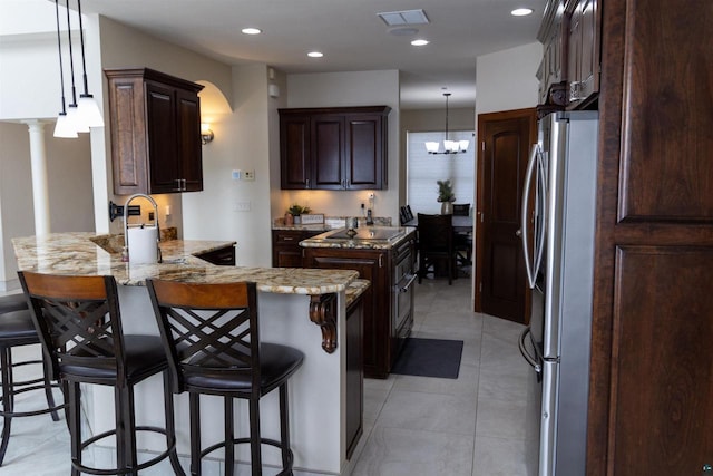 7926 S County Rd A, Superior, WI 54880 - kitchen with freestanding refrigerator, a peninsula, dark brown cabinetry, light stone countertops, and a kitchen breakfast bar