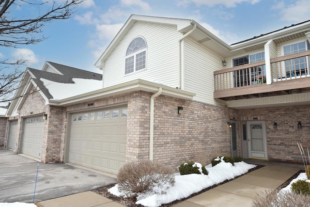 view of front of home featuring brick siding, driveway, and a balcony