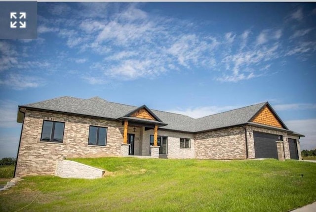 view of front of property featuring an attached garage, brick siding, roof with shingles, and a front yard