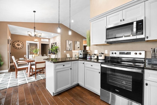 kitchen featuring hanging light fixtures, appliances with stainless steel finishes, dark wood-type flooring, vaulted ceiling, and a peninsula