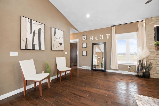 living area with high vaulted ceiling, visible vents, baseboards, and wood finished floors