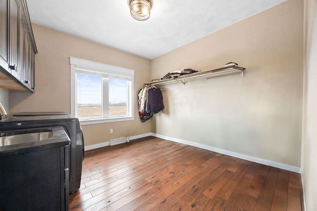 laundry room featuring visible vents, baseboards, cabinet space, wood-type flooring, and washing machine and clothes dryer