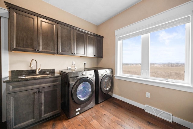 laundry area with cabinet space, visible vents, light wood-type flooring, washing machine and dryer, and a sink