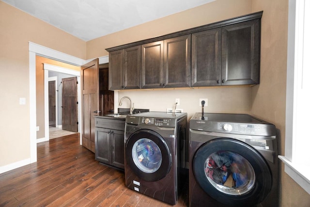 laundry area featuring dark wood finished floors, cabinet space, a sink, washer and dryer, and baseboards