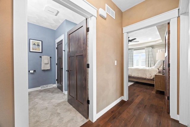 hallway featuring wood-type flooring, visible vents, and baseboards