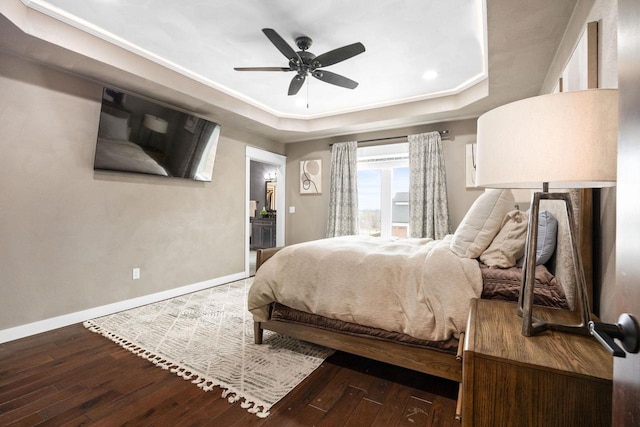 bedroom with a tray ceiling, baseboards, and hardwood / wood-style floors