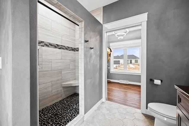 full bathroom with toilet, visible vents, vanity, baseboards, and walk in shower