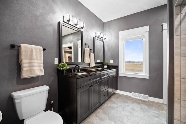 full bathroom featuring double vanity, visible vents, toilet, a sink, and baseboards