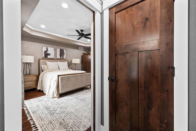 bedroom with ceiling fan, a raised ceiling, wood finished floors, and recessed lighting