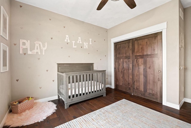 unfurnished bedroom featuring a nursery area, a closet, baseboards, and hardwood / wood-style flooring