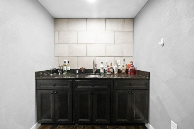 bar featuring baseboards, a sink, and a bar