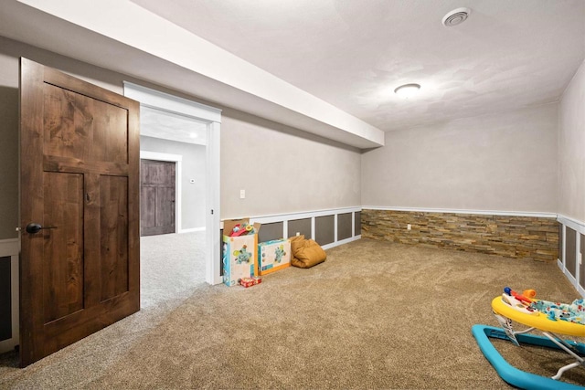 game room with a wainscoted wall and carpet flooring