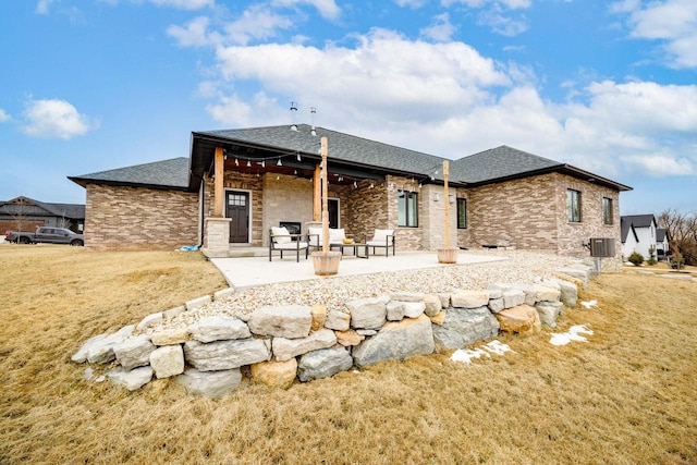 back of house featuring a patio, a shingled roof, stone siding, and central air condition unit