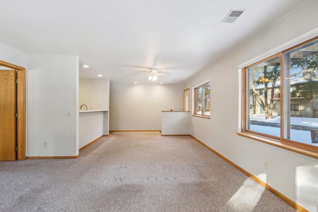 spare room with a ceiling fan, light colored carpet, visible vents, and baseboards