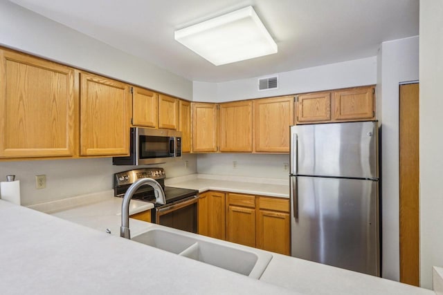 kitchen with stainless steel appliances, a sink, visible vents, light countertops, and brown cabinets