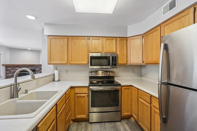 kitchen with stainless steel appliances, light countertops, visible vents, a sink, and light wood-type flooring